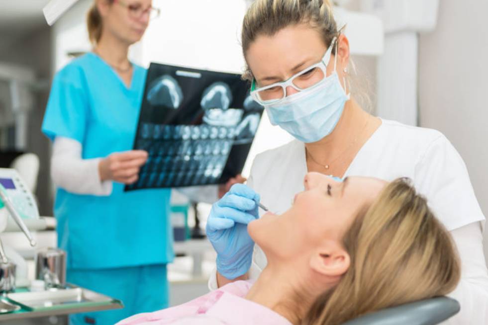 Dentist giving an examination and another looking at x-rays